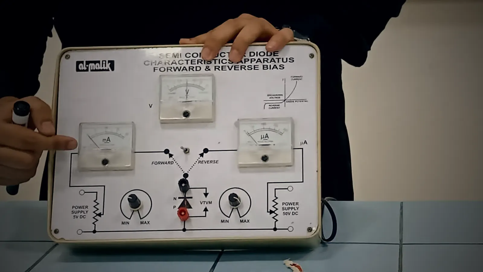 Hammad Shaukat pointing to the milliammeter on a diode forward and reverse bias apparatus